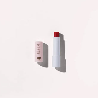 Stick of Whamisa Organic Flower Lip Balm over a white background